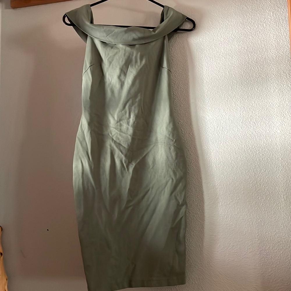 Green form fitting dress with off the shoulder sleeves.